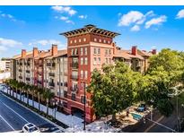 Beautiful multi-story building featuring brick accents, balconies, and lush green trees around the perimeter at 911 N Orange Ave # 550, Orlando, FL 32801