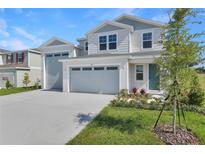 Charming two-story home featuring an attached two-car garage, fresh landscaping, and a welcoming blue front door at 1107 Olivine Ave, Dundee, FL 33838