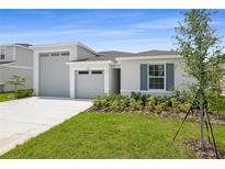 Charming single Gathering home featuring a well manicured lawn, attached two-car garage, and blue shutters at 1122 Olivine Ave, Dundee, FL 33838