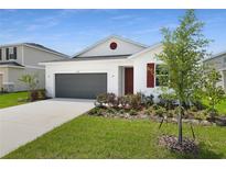 Charming one-story home with a two-car garage, landscaped yard, and white exterior at 1134 Olivine Ave, Dundee, FL 33838