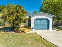 Charming home with a light blue garage door, front deck, and lush landscaping at 1211 Shawnee Dr, Kissimmee, FL 34744