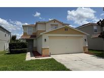 Inviting two-story home featuring a large two-car garage, well-maintained lawn, and colorful exterior paint scheme at 133 Rona Ln, Davenport, FL 33897