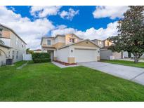 Two-story home with attached two-car garage and a well-manicured lawn in a suburban neighborhood at 133 Rona Ln, Davenport, FL 33897