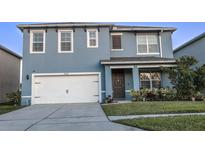 Inviting blue two-story home with a well-manicured lawn, garage, and charming front entrance at 2532 Ryland Falls Dr, Lakeland, FL 33811