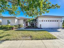 Charming single-story home featuring a manicured lawn, lush landscaping and a brick-paved driveway at 657 Shorehaven Dr, Poinciana, FL 34759