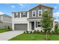 Charming two-story home featuring gray and white colors, a landscaped yard, and a two car garage at 1031 Wisteria Way, Dundee, FL 33838