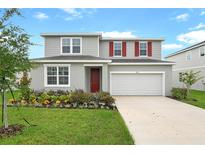 Charming two-story home with a well-manicured lawn and colorful flower beds at 1035 Wisteria Way, Dundee, FL 33838