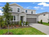 Two-story home with gray siding, stone accents, manicured lawn, and an attached two-car garage in a suburban neighborhood at 1118 Olivine Ave, Dundee, FL 33838