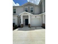 Modern townhouse exterior features a front-entry garage, neutral stucco and stone accents at 2414 Skyline Loop, Kissimmee, FL 34758