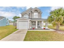 Charming two-story home featuring a well-manicured lawn, attached garage, and inviting front porch at 2500 Davenport Cirlce Cir, Kissimmee, FL 34746
