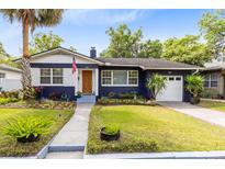 Charming blue home featuring a manicured lawn, blooming flowers, and a welcoming walkway at 1510 E Ridgewood St, Orlando, FL 32803