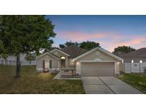Charming single-story home with a well-manicured lawn and a two-car garage at dusk at 323 Azincourt Ln, Kissimmee, FL 34759