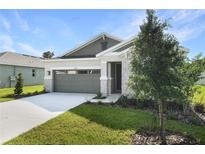 Charming home featuring stone accents, a gray garage door, and a well-manicured lawn at 4075 Bannock Ave, Tavares, FL 32778
