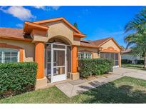 Charming single-story home showcasing a well-manicured front yard, terra cotta roof, and inviting screened porch entrance at 6017 Hickory Grove Ln, Port Orange, FL 32128