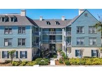 Exterior of condo complex featuring three floors with balconies, blue siding, and manicured landscaping at 611 Campus St # 340, Celebration, FL 34747