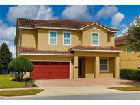 Charming two-story home features a red tile roof, red garage door, and meticulously maintained landscaping at 7664 Wilmington Loop, Kissimmee, FL 34747
