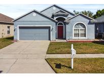 Charming single-Gathering home featuring a gray exterior, two-car garage, and a red front door at 7733 Beridale Ct, Orlando, FL 32818