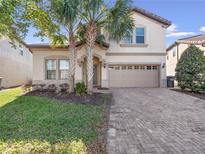 Charming home featuring a brick driveway, well-maintained lawn, and a two-car garage at 8879 Qin Loop, Kissimmee, FL 34747