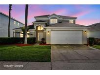 Charming two-story home featuring a manicured lawn, a two-car garage, and a beautifully lit entrance at 1048 Lake Berkley Dr, Kissimmee, FL 34746