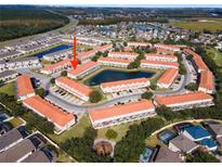 A beautiful aerial view of townhomes surrounding a pond in a well-maintained community with mature trees and landscaping at 1149 S Beach Cir, Kissimmee, FL 34746
