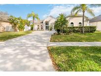 Inviting single-story home featuring a well-manicured lawn, swaying palm trees, and a spacious driveway leading to a grand entrance at 1923 Lazy Oaks Loop, St Cloud, FL 34771