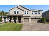 Charming two-story home with a well-manicured lawn and a three-car garage on a brick driveway at 2017 Camden Loop, Davenport, FL 33837