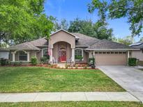 Beautiful single-story home featuring well-manicured lawn, tasteful landscaping, and a charming red front door at 4907 Raylene Way, St Cloud, FL 34771