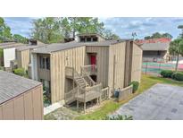 Inviting multi-level townhome featuring exterior staircase with red door and views of the community's tennis courts at 5316 Burning Tree Dr # A09-2, Orlando, FL 32811