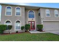 Two story home with large windows and a red double door at 907 Gloucester Ct, Kissimmee, FL 34758