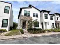 Contemporary two-story home featuring a stone facade, manicured landscaping, and a brick walkway at 236 Villa Domani Cir, Davenport, FL 33896