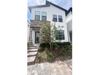 Modern two-story home with stone accents and manicured landscaping at 236 Villa Domani Cir, Davenport, FL 33896