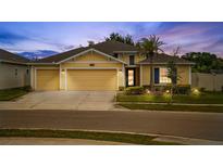 Charming yellow home with a three-car garage, palm tree, and well-manicured lawn at 1848 Ancestry Trl, Kissimmee, FL 34746