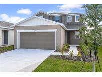 Charming two-story home featuring a gray-brown exterior, a two-car garage, and fresh landscaping at 6381 Clover St, Lake Hamilton, FL 33851