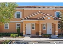 Charming townhome featuring a stucco facade, tiled roof, and well-manicured landscaping, unit #2620 at 2618 Roadster Ln, Kissimmee, FL 34746
