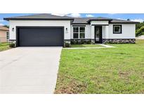 Charming single-story home boasts a modern design with a gray garage door and well-manicured lawn at 308 Miami Ln, Kissimmee, FL 34759