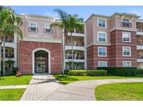 Beautiful condo building featuring a gated entry, lush landscaping, and classic architectural design with a pink exterior at 5012 Shoreway Loop # 205, Orlando, FL 32819