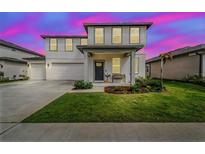 Charming two-story home with a well-manicured lawn and a two-car garage against a vibrant twilight sky at 2350 Gold Dust Dr, Minneola, FL 34715