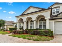 Charming stucco home featuring an arched entryway, attached garage, and well-maintained landscaping at 3852 Brantley Place Cir, Apopka, FL 32703