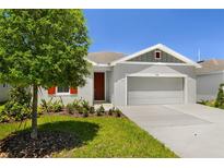 Charming single-Gathering home featuring a well-manicured lawn, gray exterior paint, and an attached two-car garage at 1749 Carnelian St, Deland, FL 32720