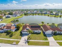An aerial view showcases this lakeside home with lush landscaping and a tranquil lake view at 2322 Queenswood Cir, Kissimmee, FL 34743