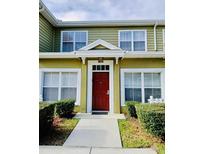 Inviting townhouse with a vibrant red front door and well-manicured landscaping at 2610 Lodi Cir # 104, Kissimmee, FL 34746