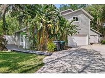 Charming home featuring two garages, lush tropical landscaping, and a welcoming gray wood finish at 13959 Marine Dr, Orlando, FL 32832