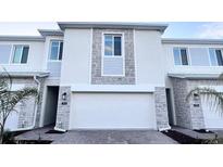 Attractive townhome featuring a two car garage, stone facade, and well manicured landscaping at 312 Nine Iron Dr, Davenport, FL 33896