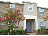 Charming two-story home featuring a blooming tree, blue front door, and well-maintained landscaping at 314 Annabelle Way, Davenport, FL 33837