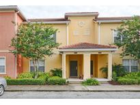 Inviting exterior of a yellow townhome with a red tile roof and well-maintained landscaping at 8971 Candy Palm Rd, Kissimmee, FL 34747