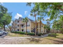 Well-maintained building featuring a yellow exterior and lush landscaping, including palm trees at 1051 S Hiawassee Rd # 2127, Orlando, FL 32835