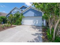 Two-story home with white garage door, blue siding, and lush landscaping in front at 4611 Eaglet Ln, Kissimmee, FL 34746