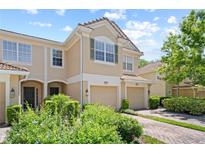 Charming townhome featuring a private garage, tile roof, and beautifully landscaped front yard at 6873 Slaven Dr, Orlando, FL 32819