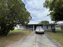 Charming one-story home with mature trees, a gray exterior, and a concrete driveway at 921 Louisiana Ave, St Cloud, FL 34769