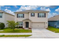 Two-story home featuring a two-car garage, manicured lawn, and neutral-toned facade at 164 Emanuelle Dr, Winter Haven, FL 33884